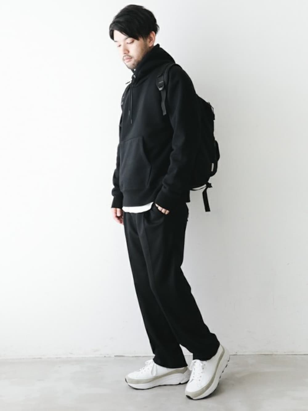 ブラック系のスウェット、ホワイト系のTシャツ/カットソー、ブラック系のスラックスを着用したメンズの秋コーディネートの1枚目の写真