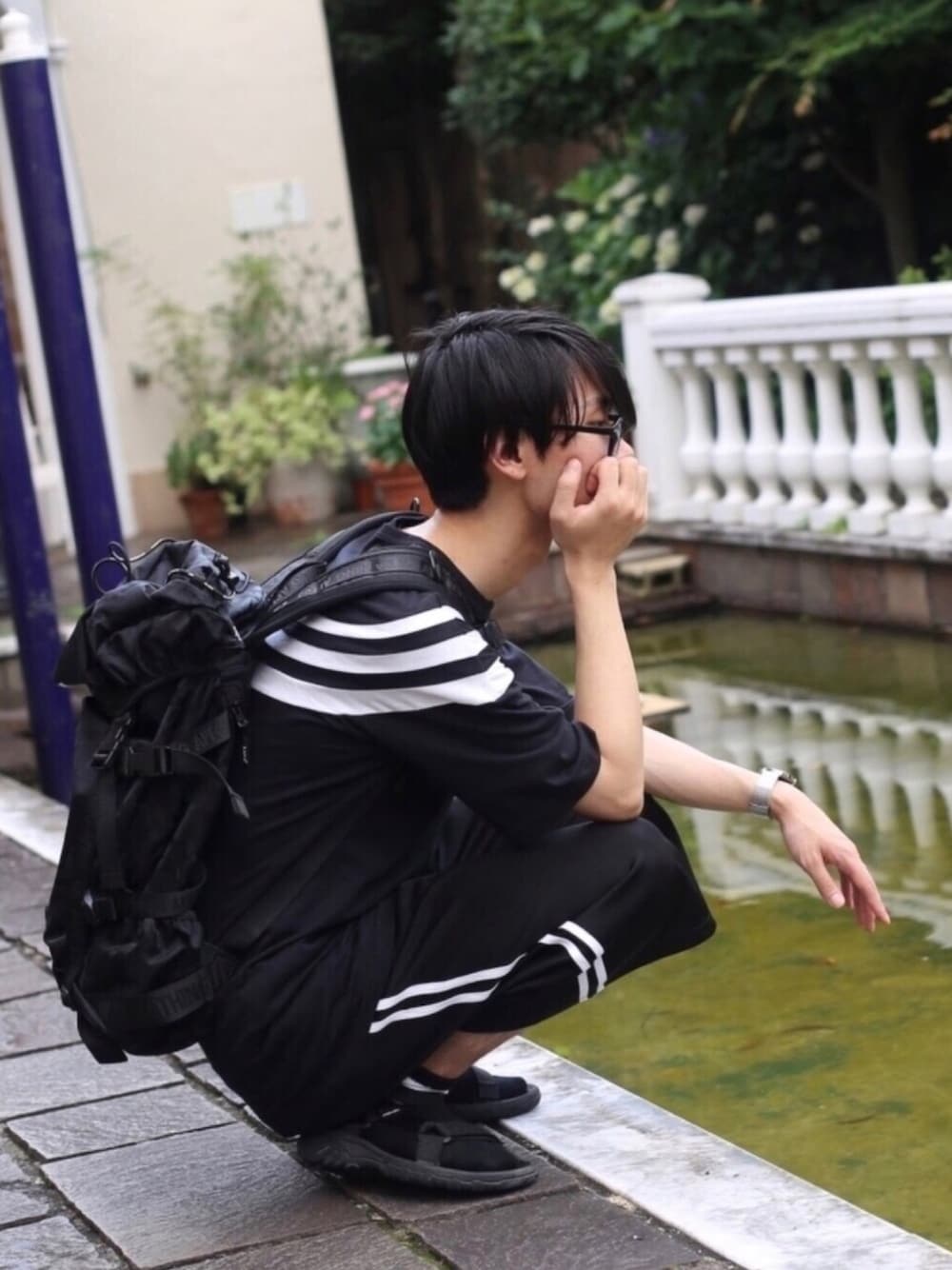 ブラック系のTシャツ/カットソー、ブラック系のバックパック/リュック、ブラック系のサンダルを着用したメンズの夏コーディネートの1枚目の写真