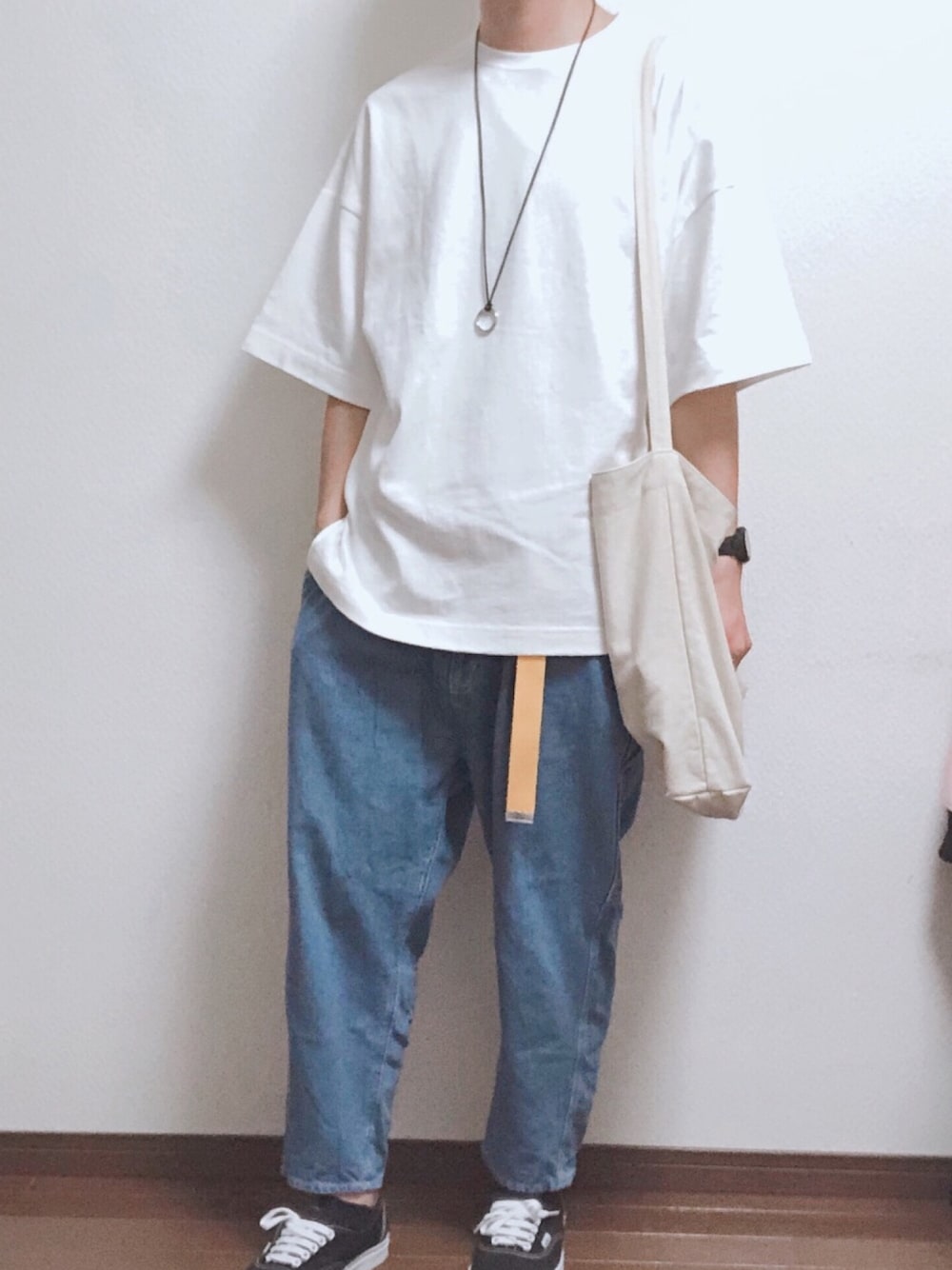 ベージュ系のトートバッグ、ホワイト系のTシャツ/カットソー、ブルー系のデニムパンツを着用したメンズの春コーディネートの1枚目の写真