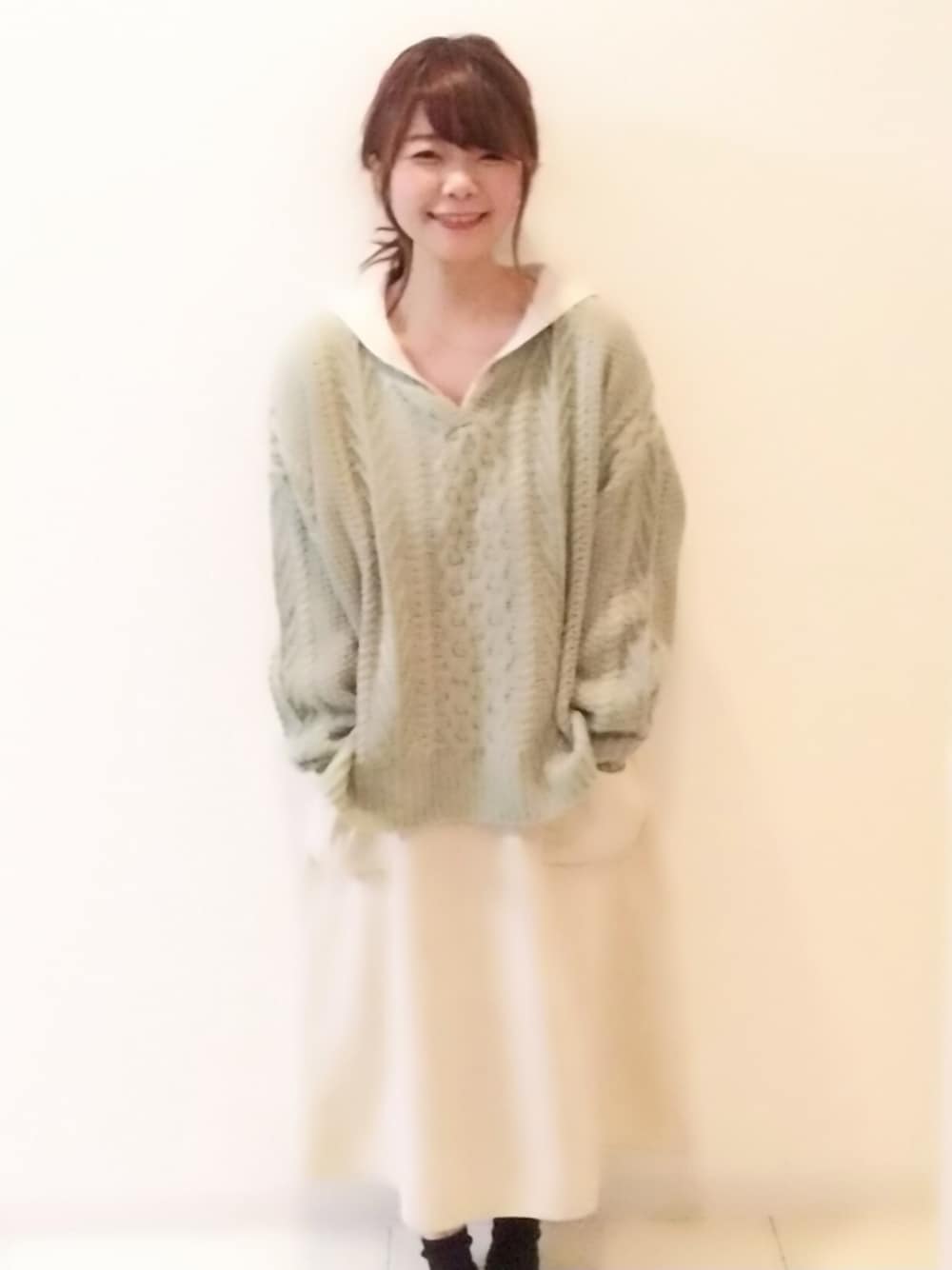 グリーン系のニット/セーター、ホワイト系のワンピースを着用したレディースの冬コーディネートの1枚目の写真