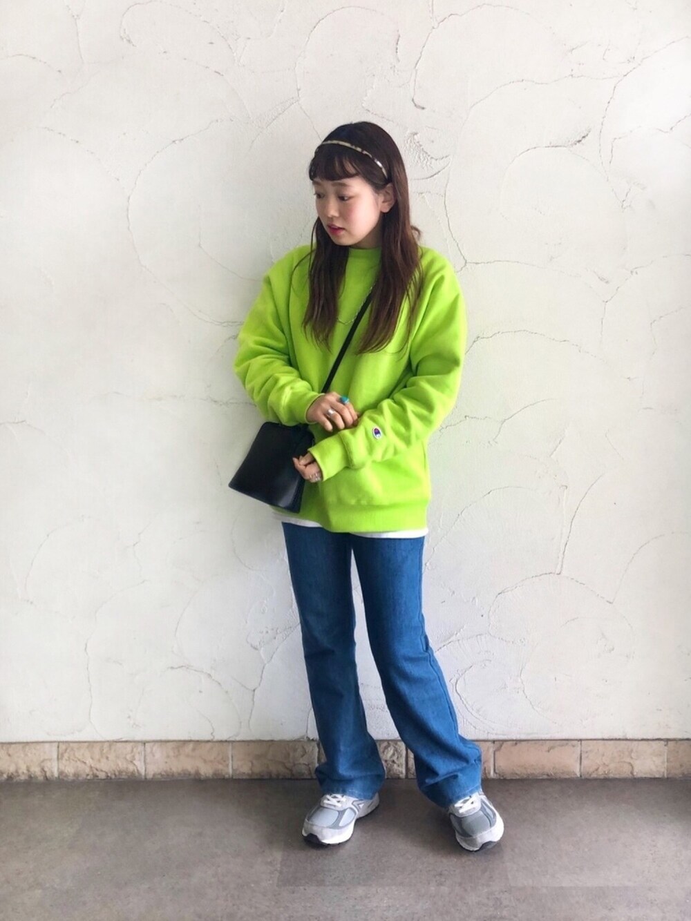 グリーン系のスウェット、ブルー系のデニムパンツ、グレー系のスニーカーを着用したレディースの春コーディネートの1枚目の写真