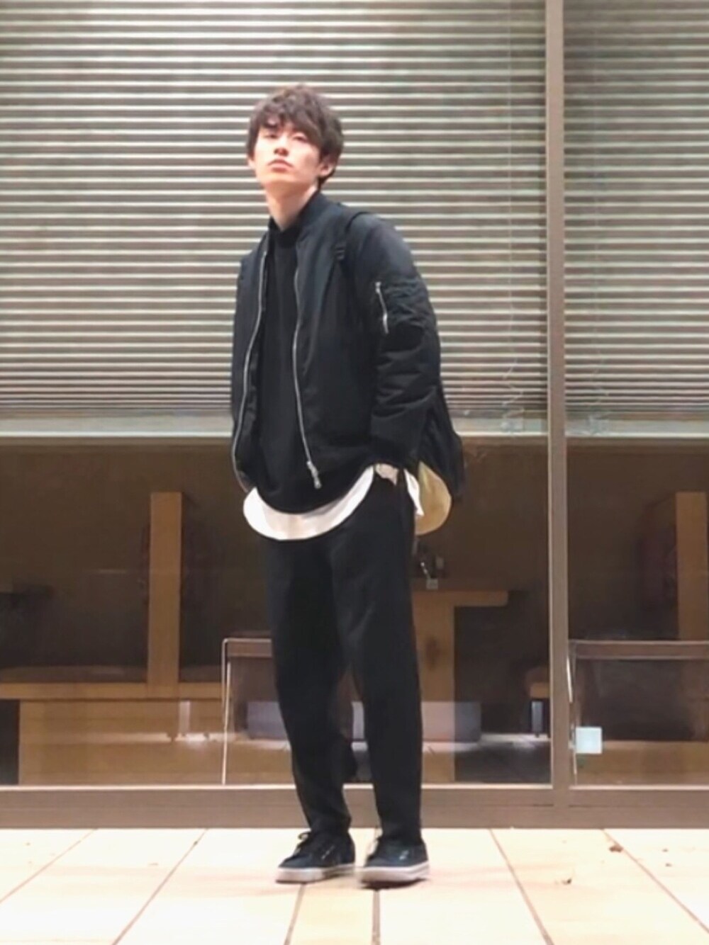 ブラック系のスラックス、ブラック系のスニーカー、ブラック系のMA-1を着用したメンズの春コーディネートの1枚目の写真