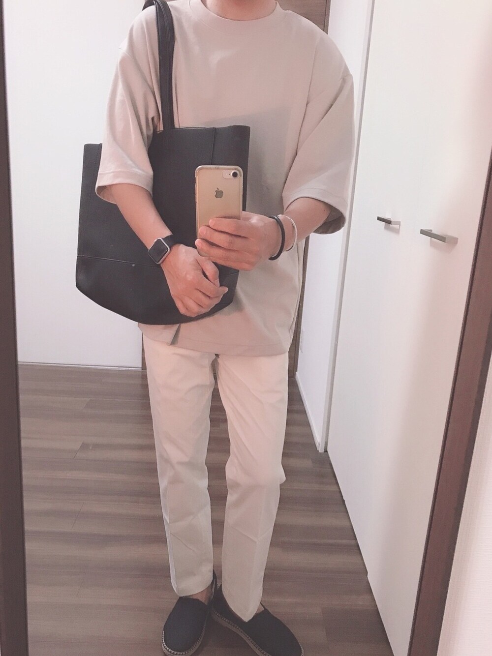 ベージュ系のTシャツ/カットソー、ブラック系のトートバッグ、ホワイト系のスラックスを着用したメンズの春コーディネートの1枚目の写真