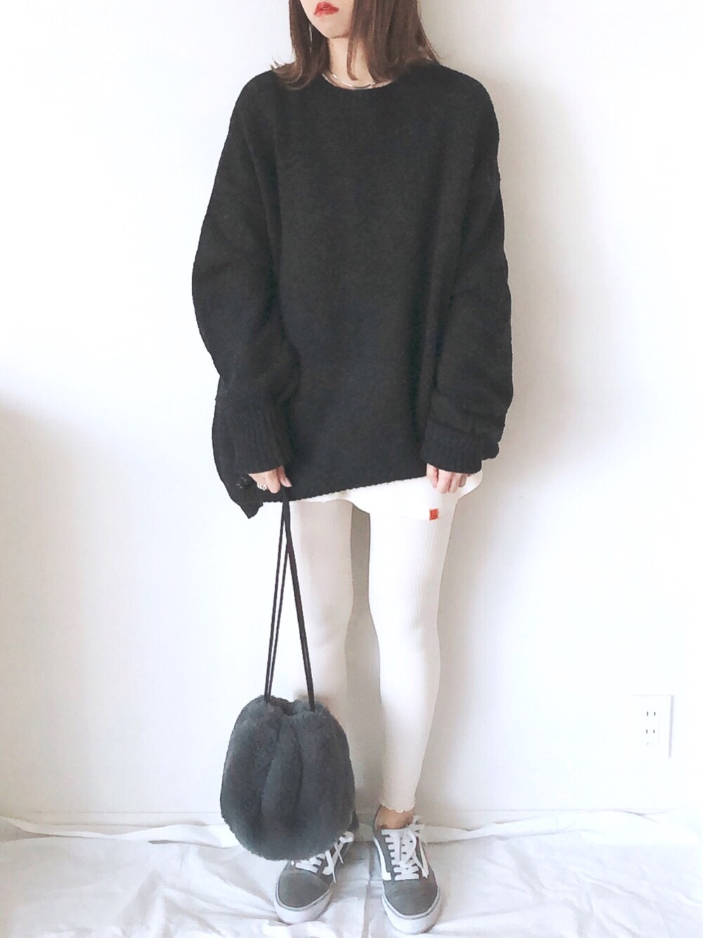 グレー系のニット/セーター、グレー系のハンドバッグ、ベージュ系のTシャツ/カットソーを着用したレディースの冬コーディネートの1枚目の写真