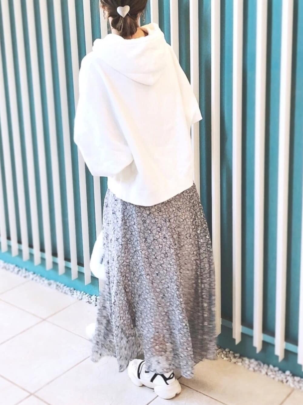 ホワイト系のパーカー、ブルー系のスカート、ホワイト系のハンドバッグを着用したレディースの冬コーディネートの1枚目の写真