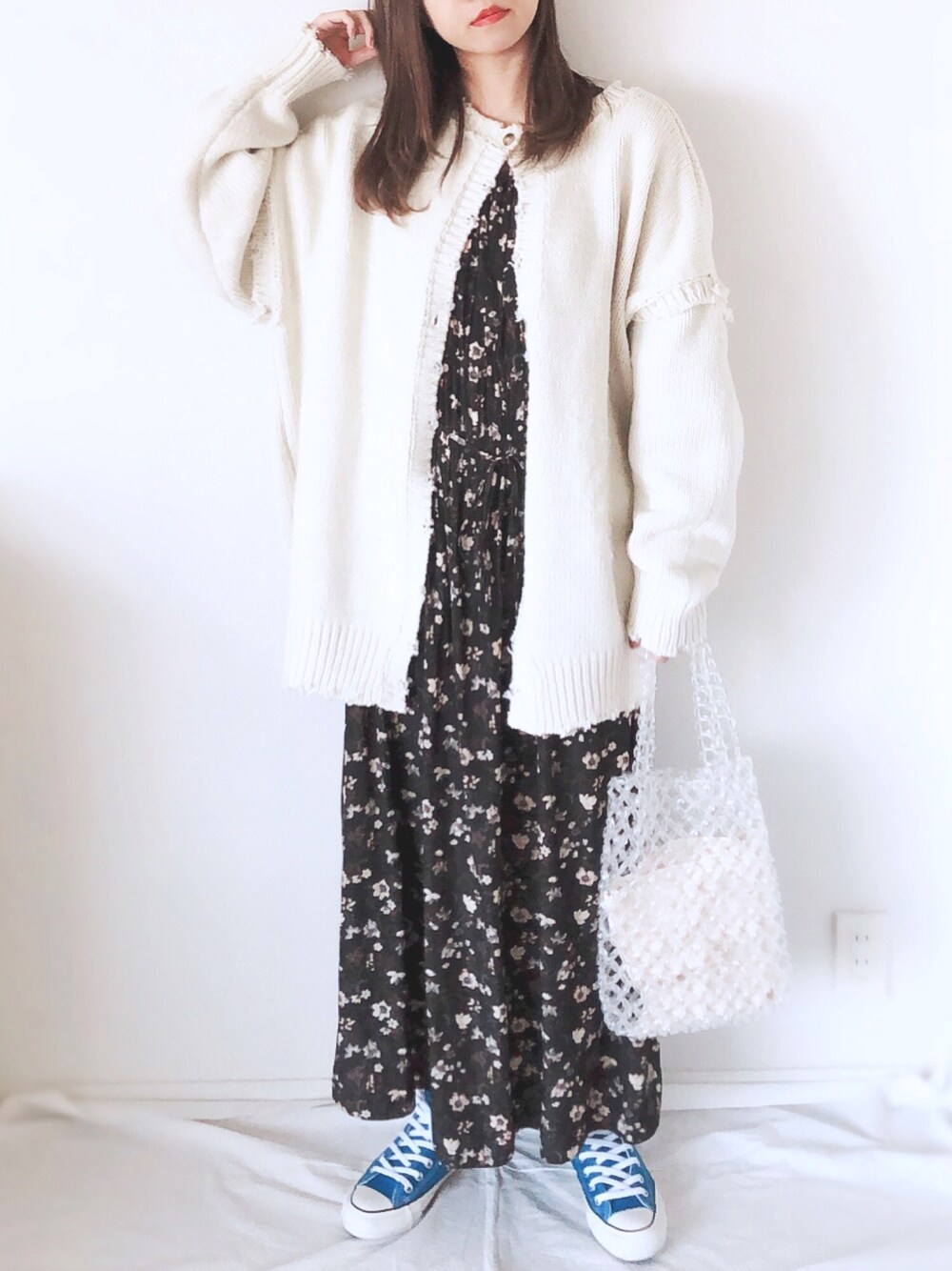 ブラック系のワンピース、ホワイト系のニット/セーター、ブルー系のスニーカーを着用したレディースの春コーディネートの1枚目の写真