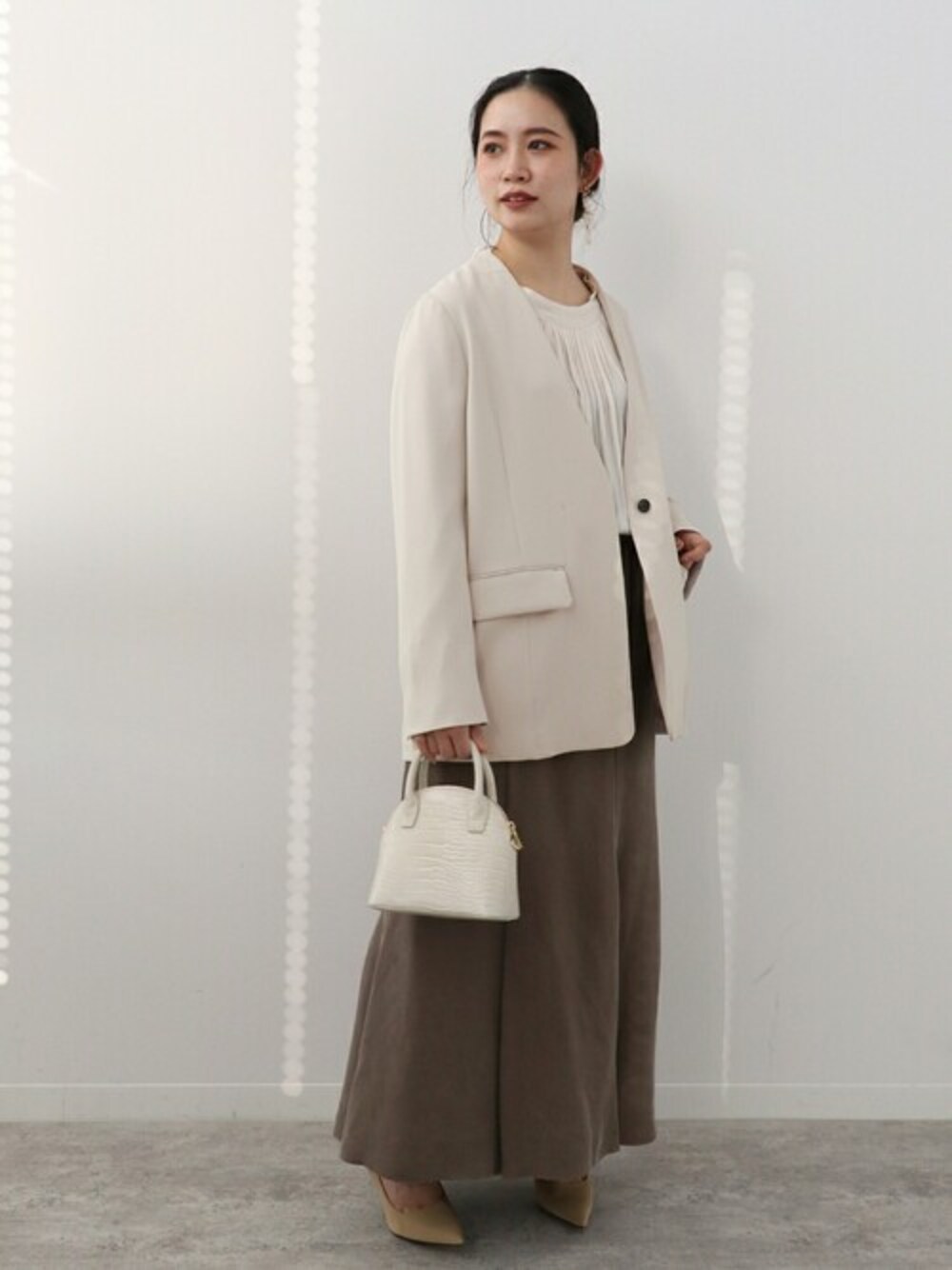 ベージュ系のノーカラージャケット、ホワイト系のシャツ/ブラウス、ブラウン系のスカートを着用したレディースの冬コーディネートの1枚目の写真