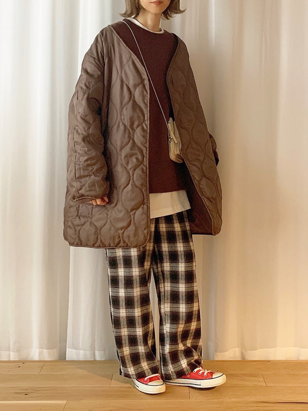 ベージュ系のノーカラーコート、ブラウン系のニット/セーター、ホワイト系のTシャツ/カットソーを着用したレディースの秋コーディネートの1枚目の写真