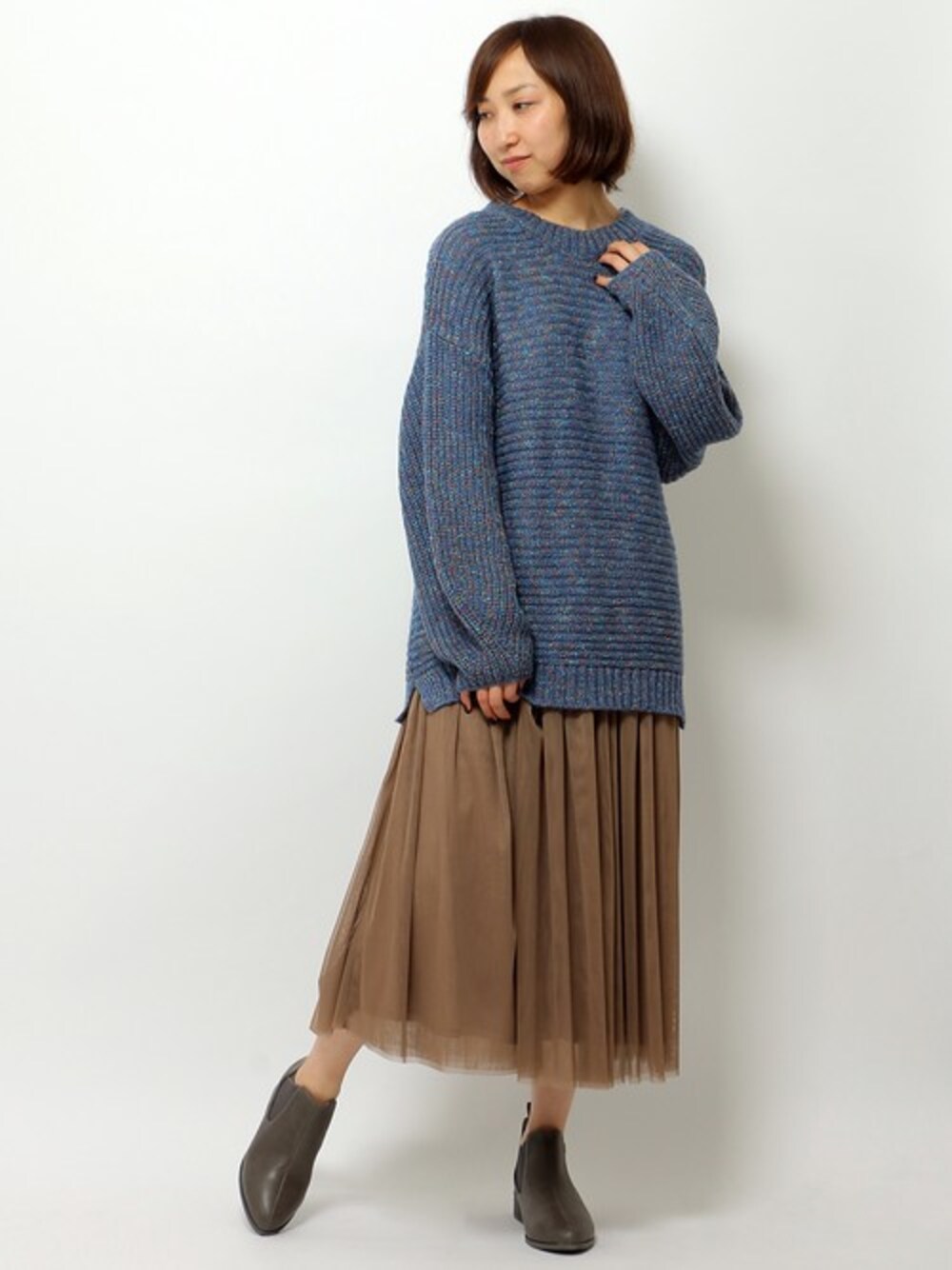 ブルー系のニット/セーター、ベージュ系のスカート、ブラウン系のブーツを着用したレディースの秋コーディネートの1枚目の写真
