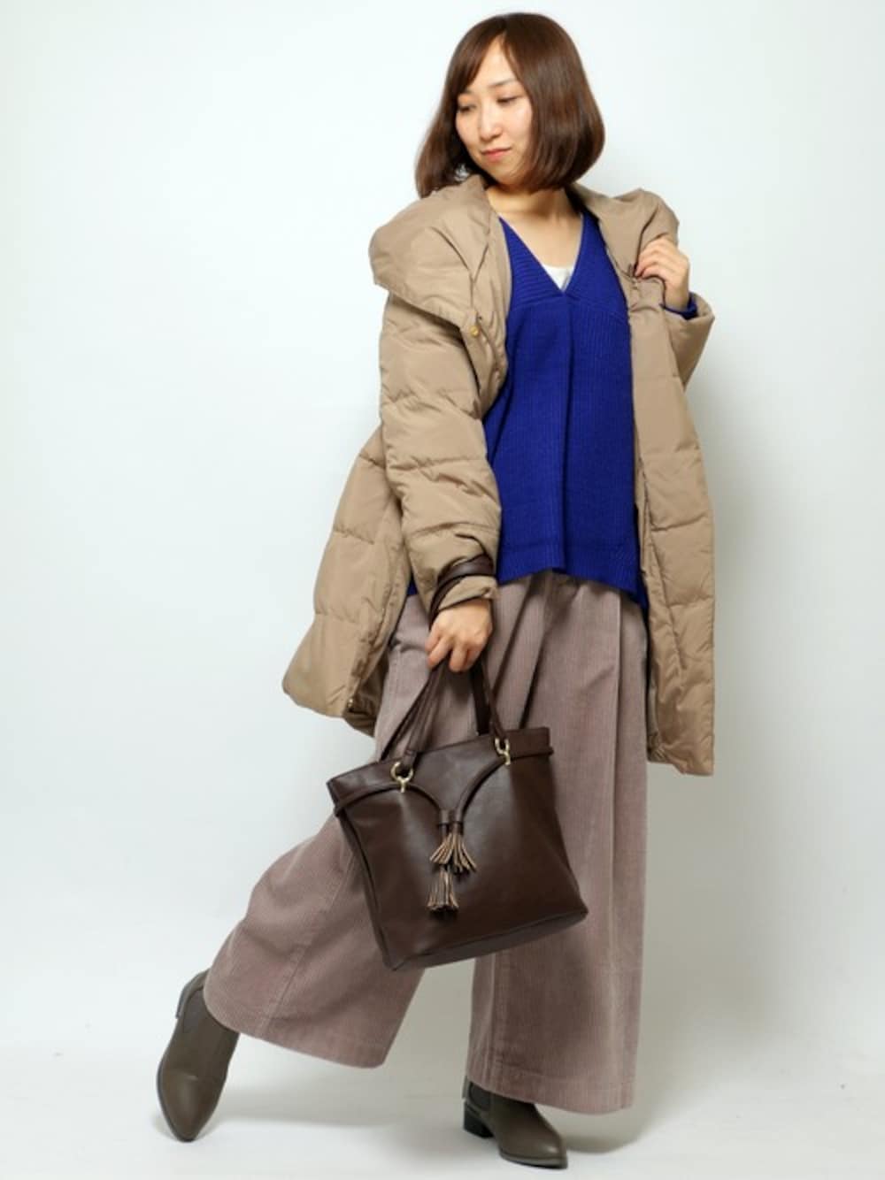 ベージュ系のダウンジャケット/コート、ブルー系のニット/セーター、グレー系のその他パンツを着用したレディースの冬コーディネートの1枚目の写真