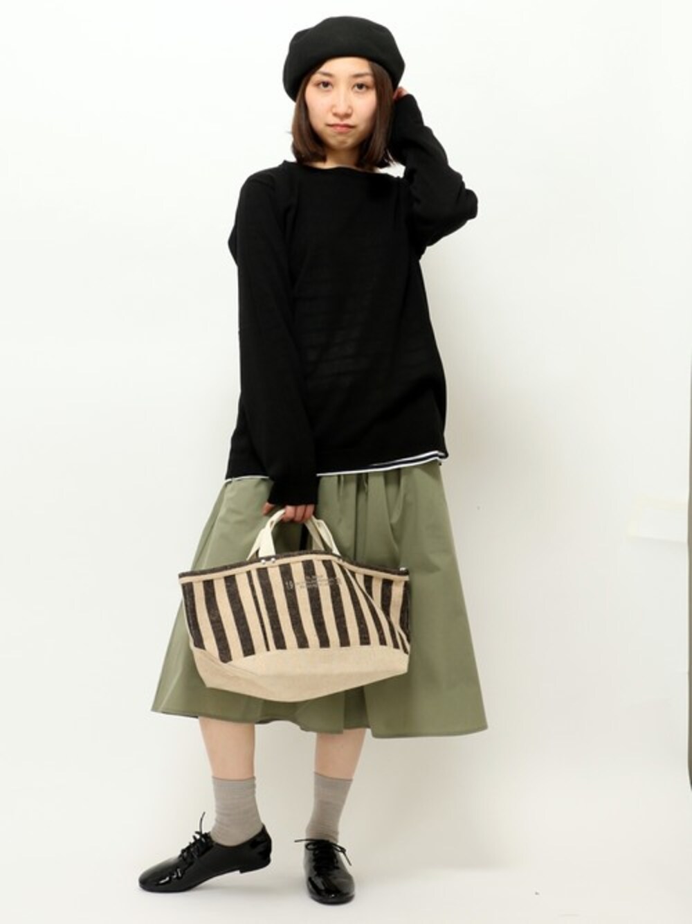 ブラック系のトートバッグ、ブルー系のTシャツ/カットソー、グリーン系のスカートを着用したレディースの冬コーディネートの1枚目の写真