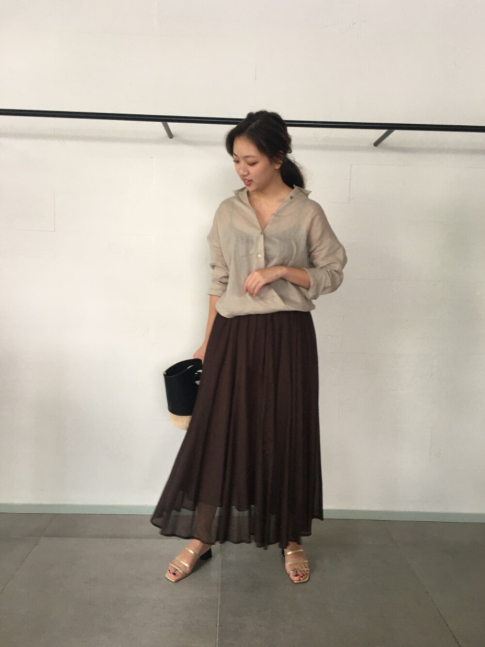 ベージュ系のシャツ/ブラウス、ブラウン系のスカート、ブラック系のかごバッグを着用したレディースの夏コーディネートの1枚目の写真