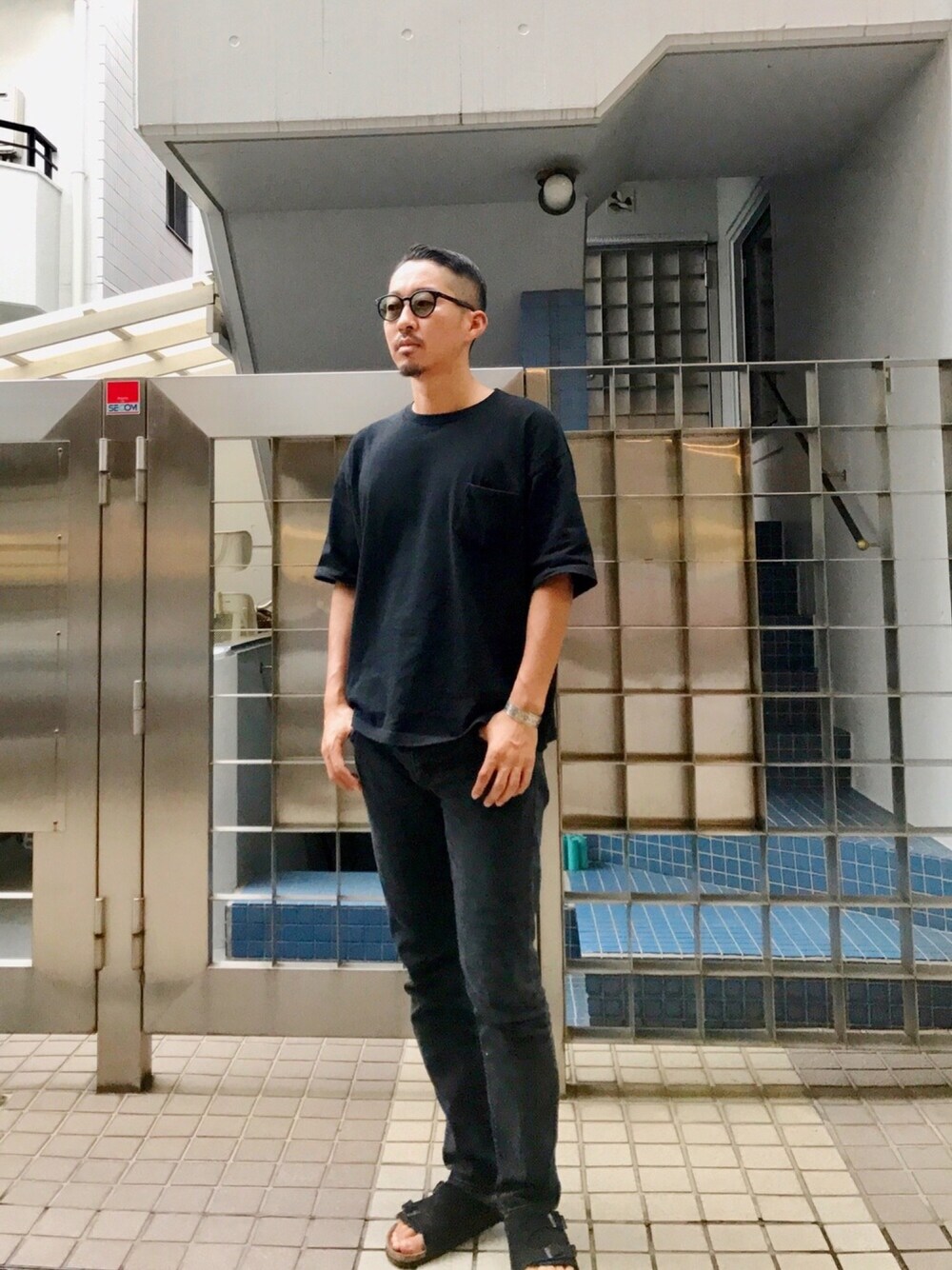 ブラック系のTシャツ/カットソー、ブラック系のデニムパンツ、ブラック系のサンダルを着用したメンズの夏コーディネートの1枚目の写真
