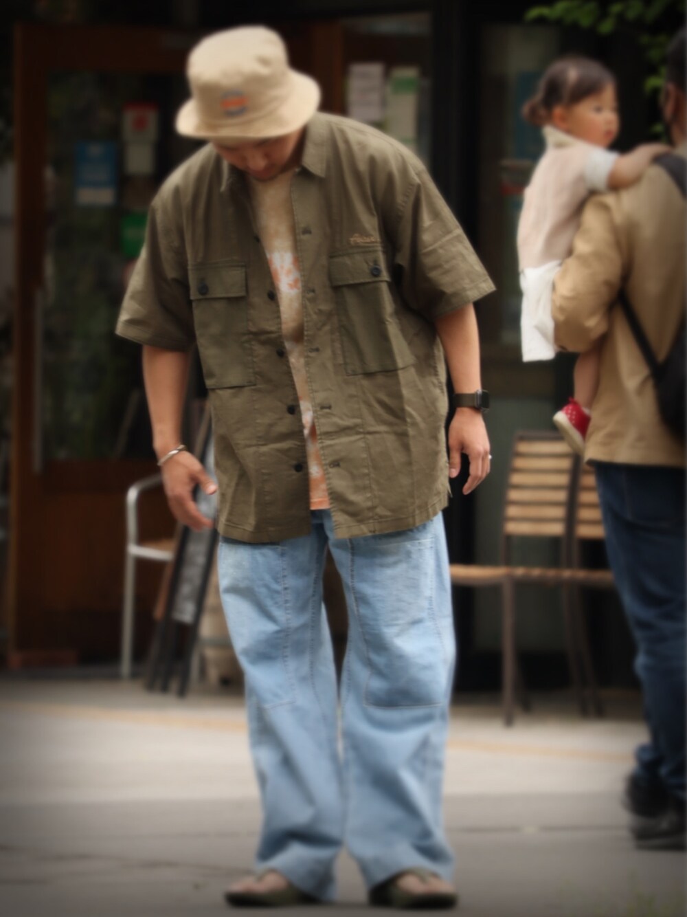 グリーン系のシャツ/ブラウス、オレンジ系のTシャツ/カットソー、ブルー系のデニムパンツを着用したメンズの春コーディネートの1枚目の写真