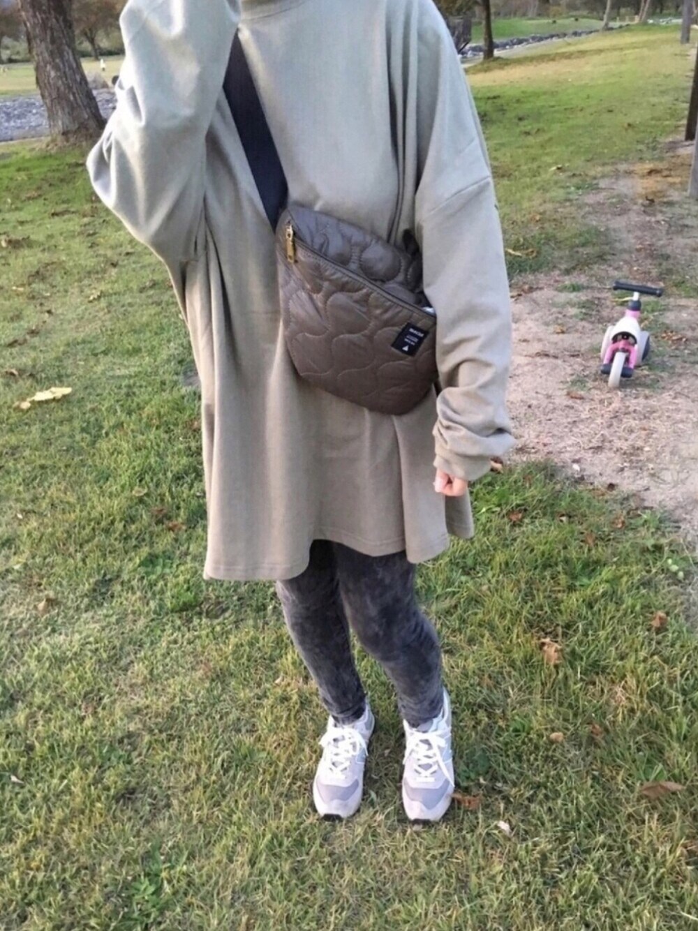 グリーン系のスウェット、グリーン系のボディバッグ/ウエストポーチ、グレー系のスニーカーを着用したレディースの冬コーディネートの1枚目の写真