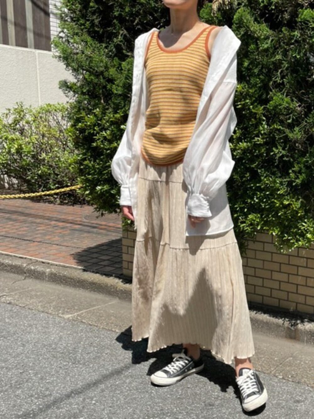 ホワイト系のシャツ/ブラウス、オレンジ系のタンクトップを着用したレディースの春コーディネートの1枚目の写真