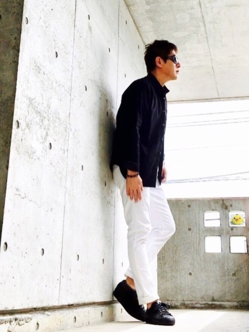 ブラック系のスニーカー、ホワイト系のデニムパンツ、ブラック系のTシャツ/カットソーを着用したメンズの夏コーディネートの1枚目の写真