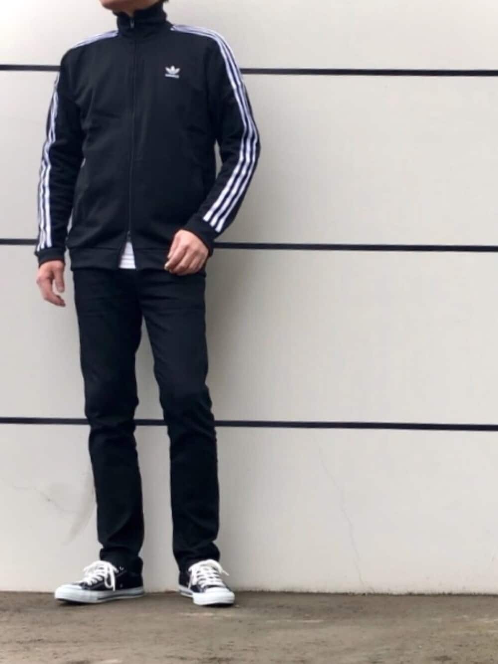 ブラック系のジャージ、ブラック系のデニムパンツ、ブラック系のスニーカーを着用したメンズの春コーディネートの1枚目の写真