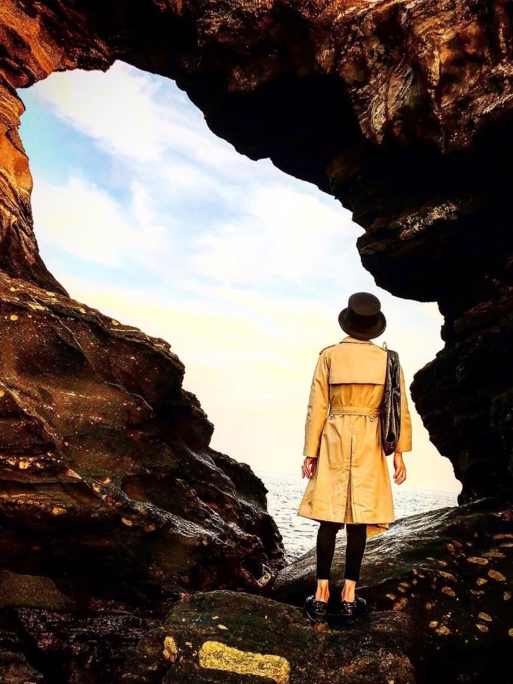 ベージュ系のトレンチコート、ブラック系のデニムパンツ、ブラック系のスニーカーを着用したメンズの秋コーディネートの1枚目の写真