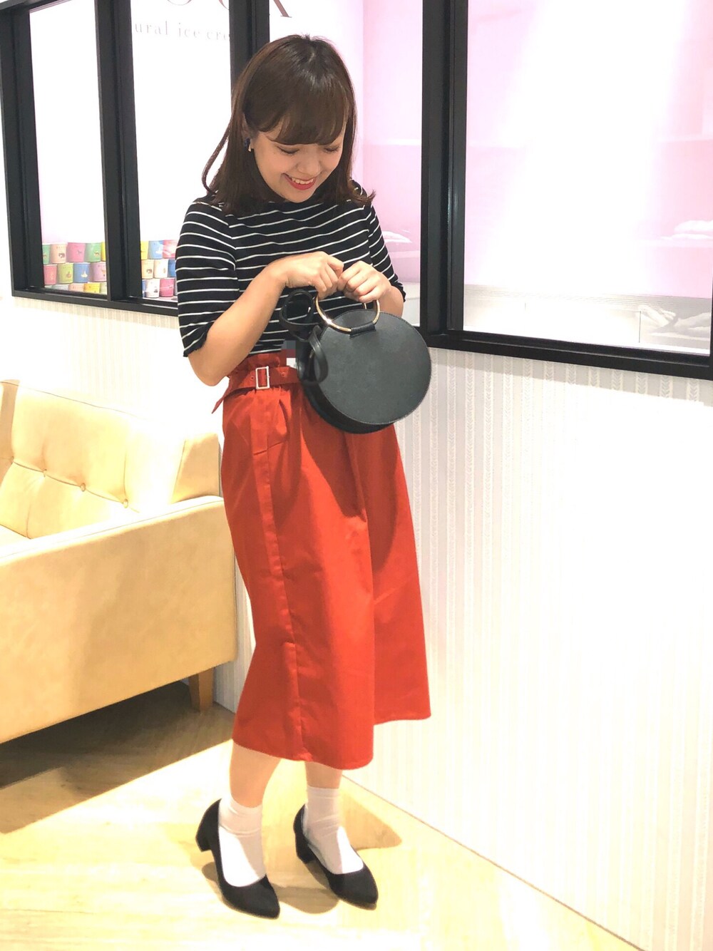 ブラック系のTシャツ/カットソー、ブラック系のショルダーバッグ、オレンジ系のスカートを着用したレディースの春コーディネートの1枚目の写真