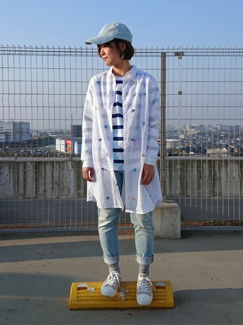 ホワイト系のシャツワンピース、ブルー系のTシャツ/カットソー、ブルー系のデニムパンツを着用したレディースの春コーディネートの1枚目の写真