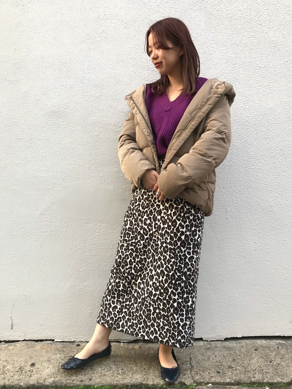 ブラウン系のスカート、ブラウン系のダウンジャケット/コート、パープル系のニット/セーターを着用したレディースの秋コーディネートの1枚目の写真