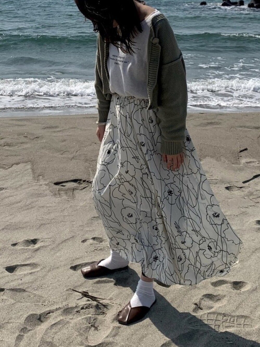 グリーン系のカーディガン/ボレロ、ホワイト系のTシャツ/カットソー、ホワイト系のスカートを着用したレディースの春コーディネートの1枚目の写真