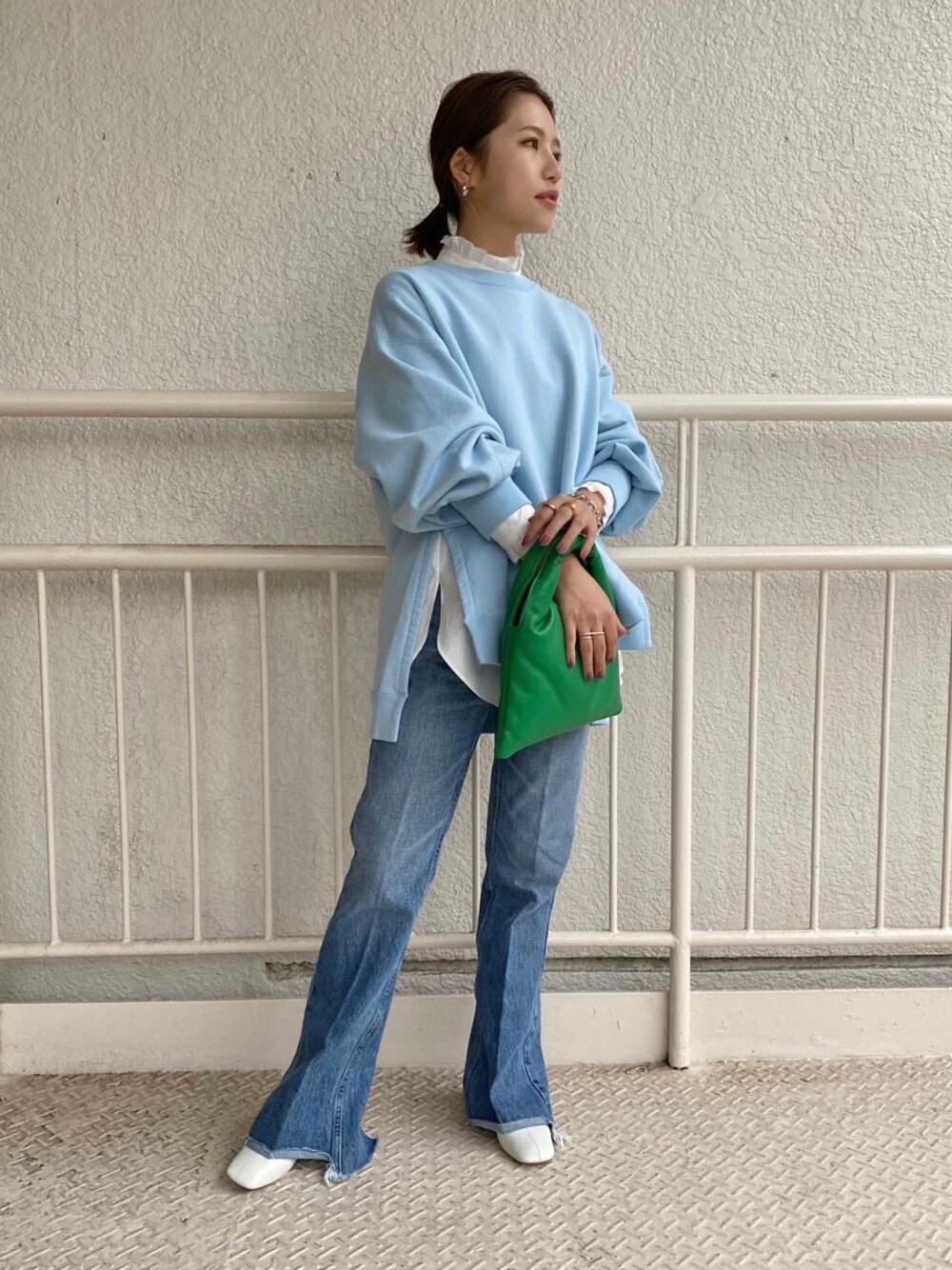 ブルー系のスウェット、グリーン系のショルダーバッグ、ブルー系のデニムパンツを着用したレディースの秋コーディネートの1枚目の写真