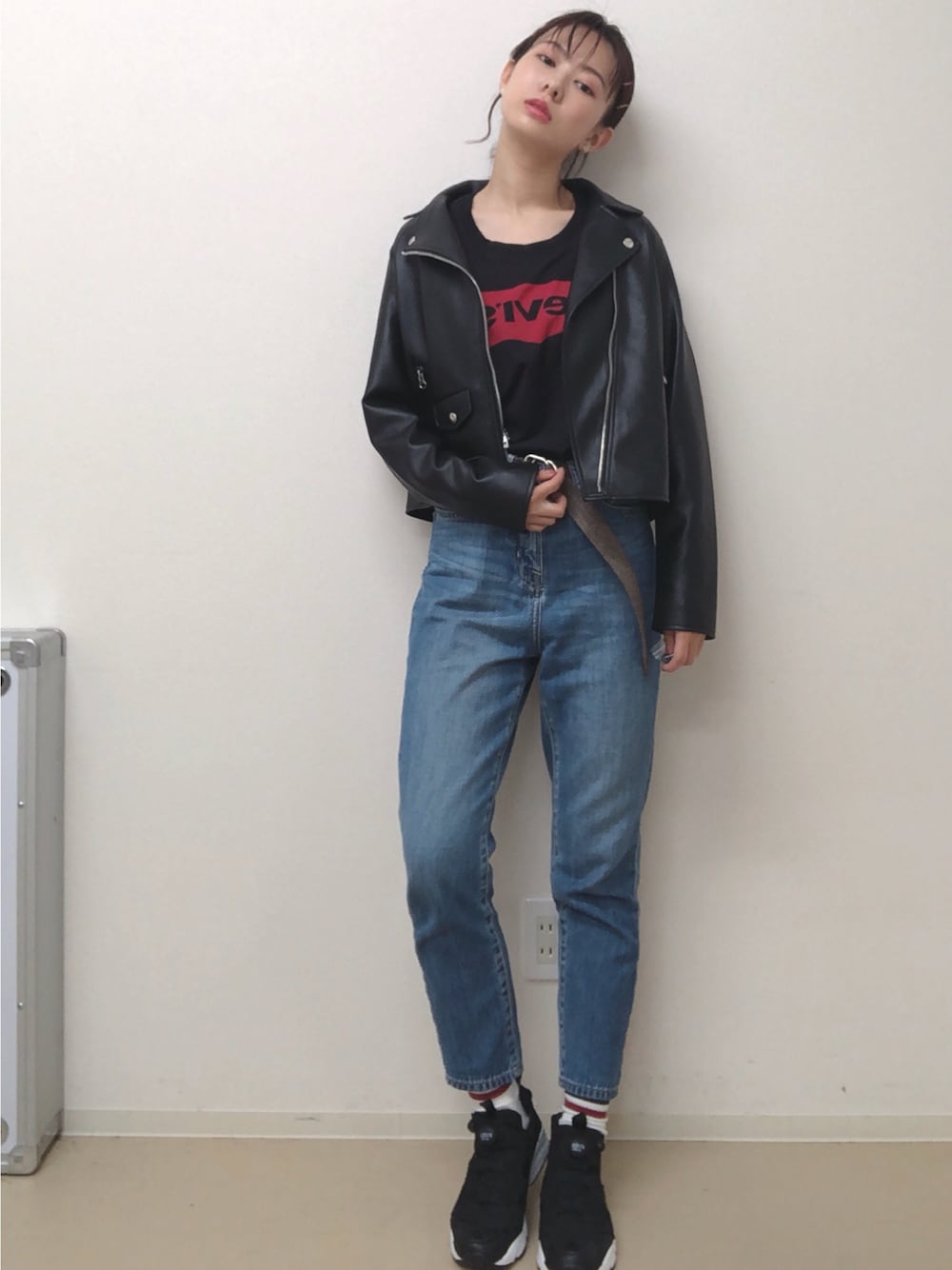 ブラック系のトップス、ブラック系のライダースジャケット、ブルー系のデニムパンツを着用したレディースの秋コーディネートの1枚目の写真