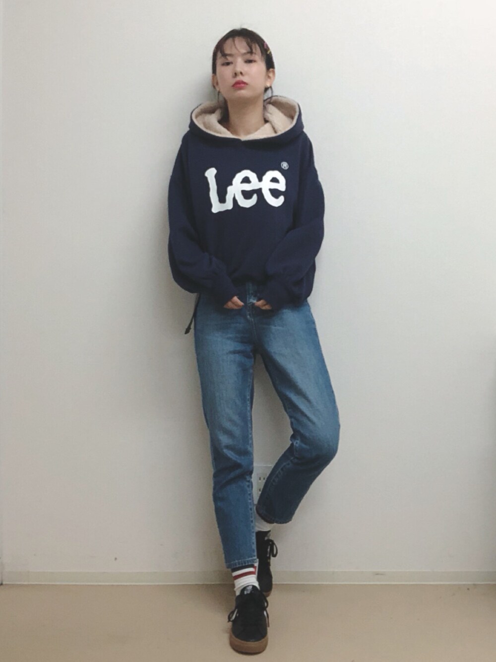 ブルー系のパーカー、ブルー系のデニムパンツ、ブラック系のスニーカーを着用したレディースの秋コーディネートの1枚目の写真