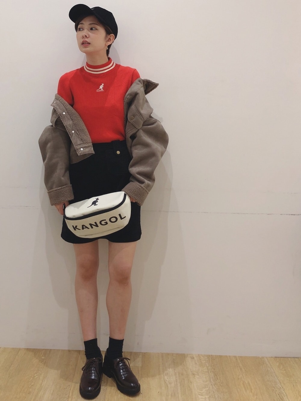 オレンジ系のニット/セーター、ブラック系のスカート、ホワイト系のバッグを着用したレディースの秋コーディネートの1枚目の写真