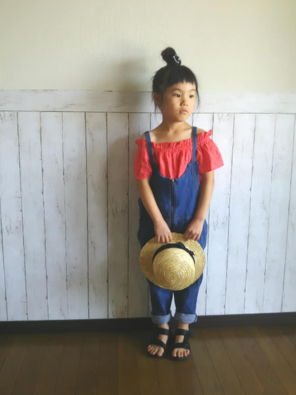 ブルー系のサロペット/オーバーオール、オレンジ系のシャツ/ブラウス、ブラック系のサンダルを着用したキッズの夏コーディネートの1枚目の写真