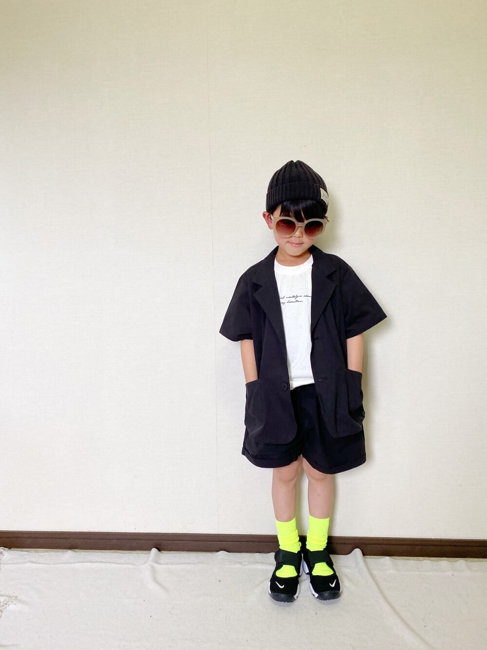 ブラック系のトップス、ホワイト系のTシャツ/カットソー、ブラック系のサンダルを着用したキッズの春コーディネートの1枚目の写真