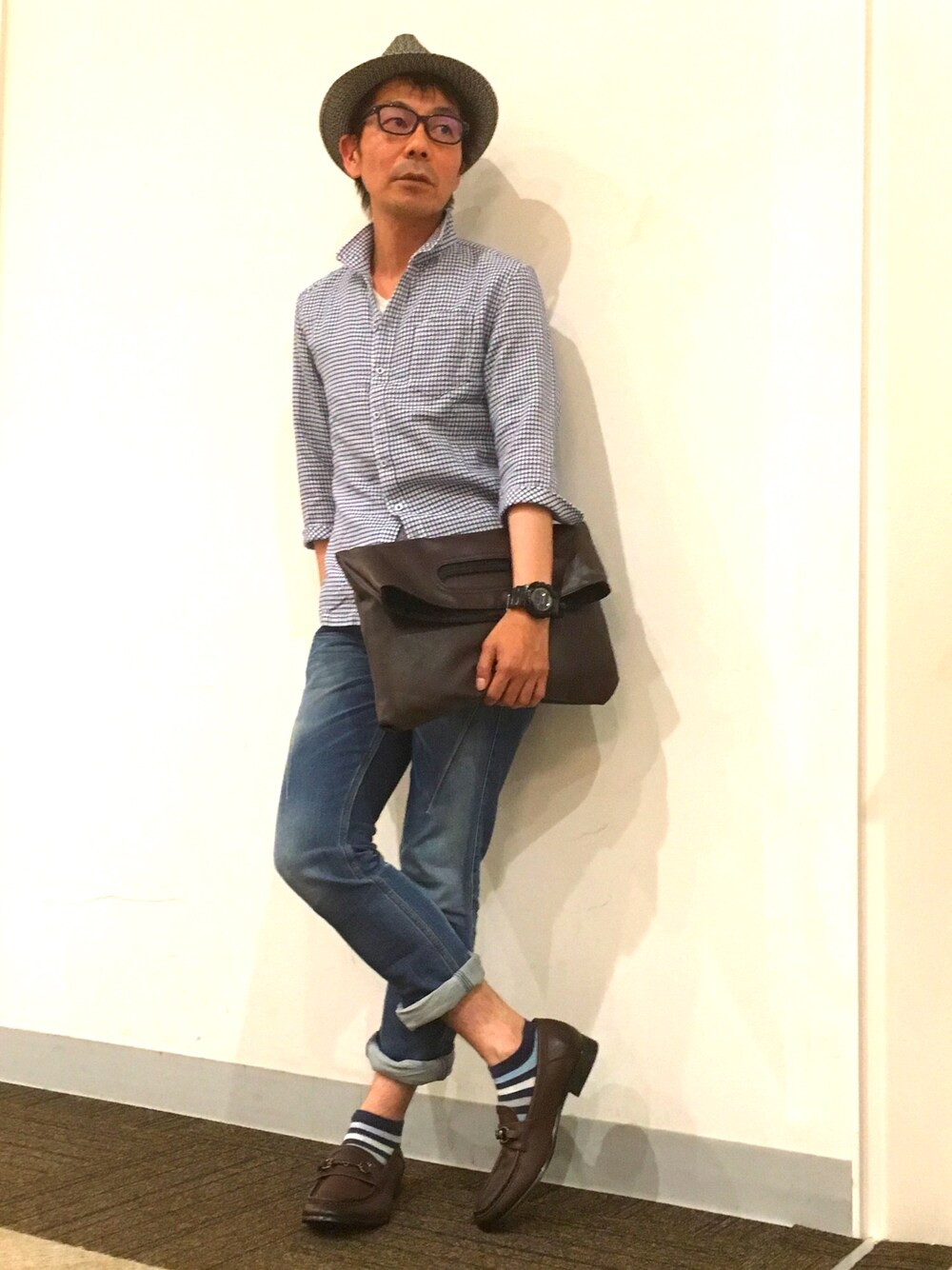 ブルー系のシャツ/ブラウス、ブラック系のクラッチバッグ、ブルー系のデニムパンツを着用したメンズの夏コーディネートの1枚目の写真