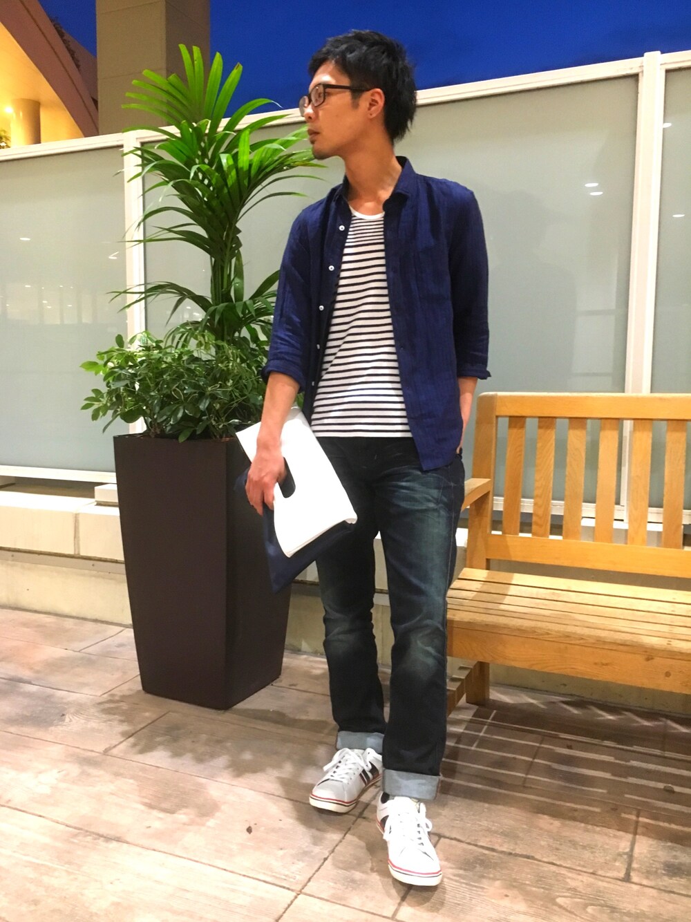 ブルー系のシャツ/ブラウス、ホワイト系のクラッチバッグ、ホワイト系のスニーカーを着用したメンズの夏コーディネートの1枚目の写真