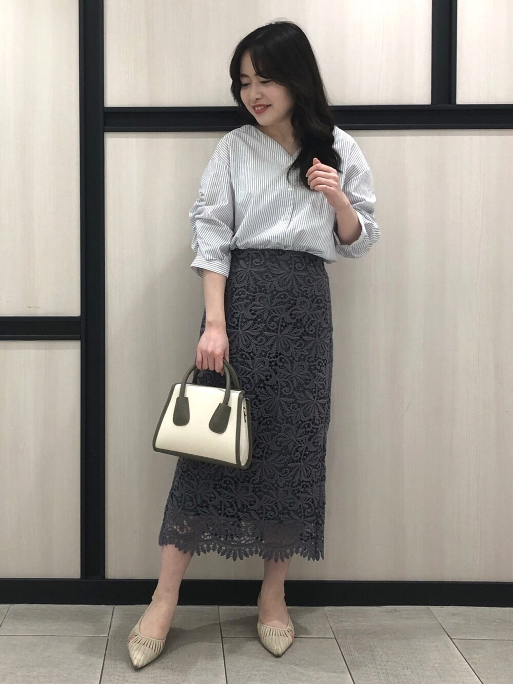 ホワイト系のシャツ/ブラウス、グレー系のスカート、グリーン系のショルダーバッグを着用したレディースの春コーディネートの1枚目の写真
