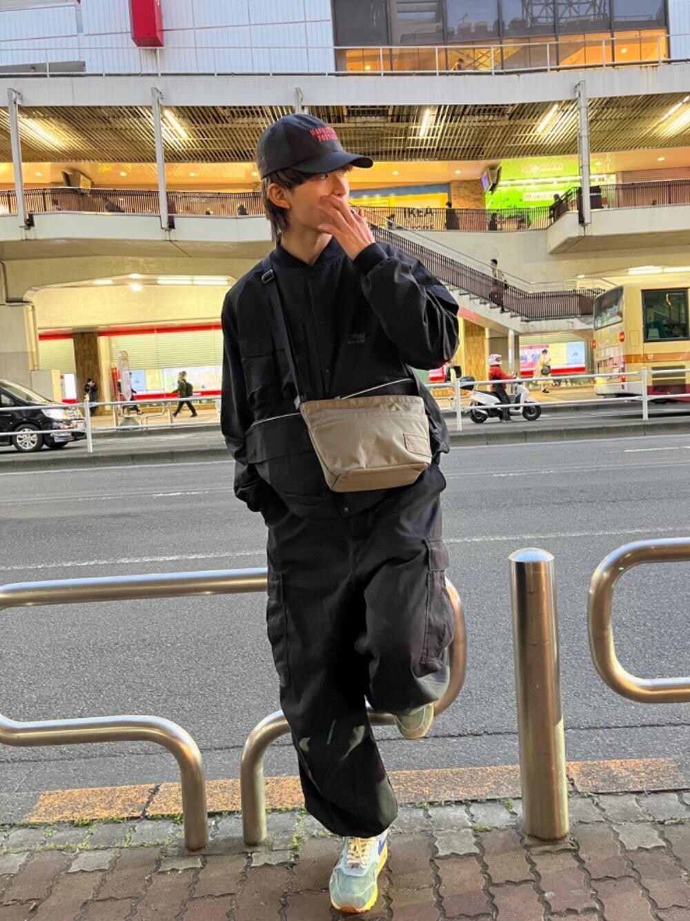 ブラック系のナイロンジャケット、グリーン系のショルダーバッグを着用したメンズの春コーディネートの1枚目の写真