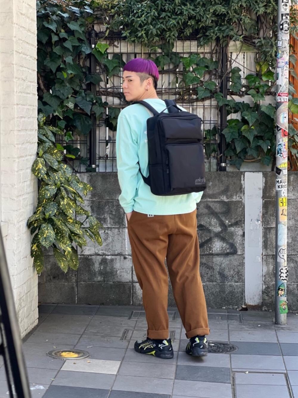 グリーン系のTシャツ/カットソー、ブラック系のバックパック/リュックを着用したメンズの春コーディネートの1枚目の写真