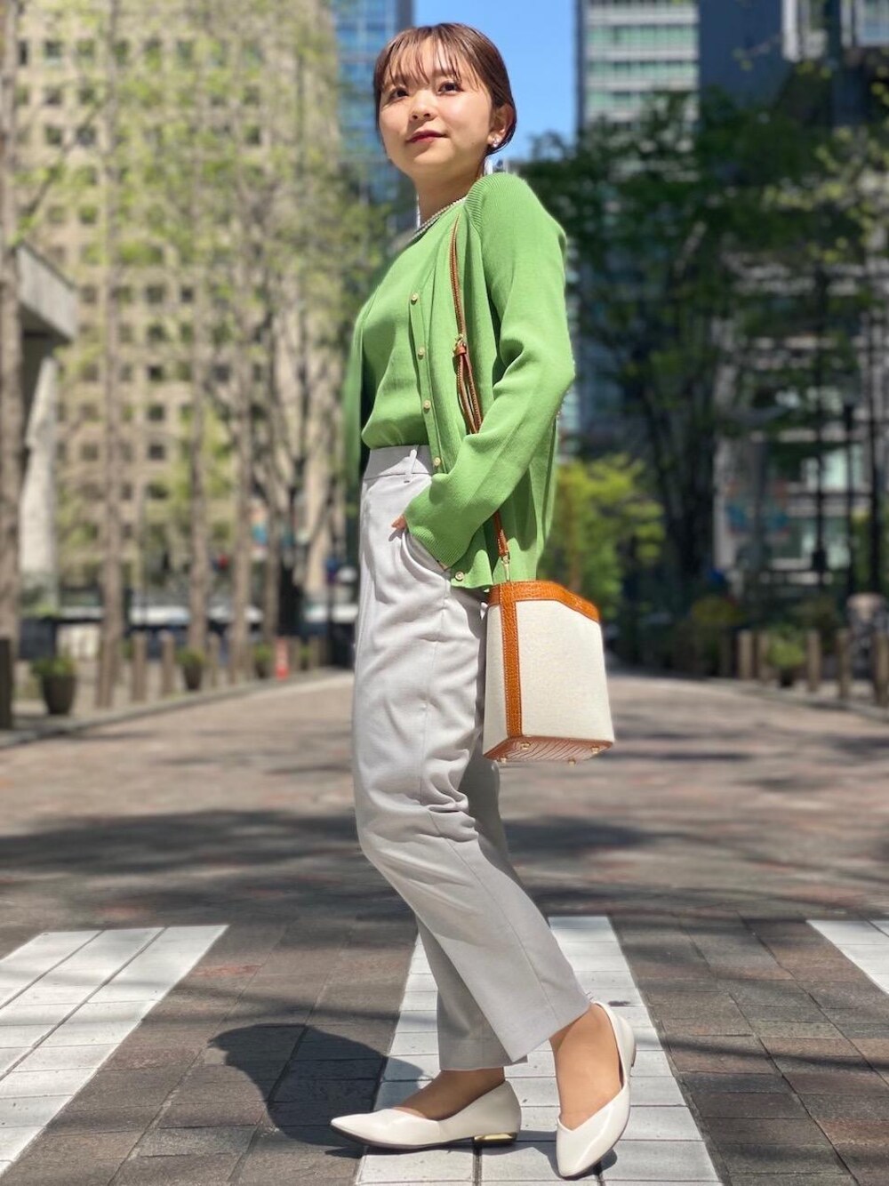 グレー系のその他パンツ、ホワイト系のパンプス、グリーン系のニット/セーターを着用したレディースの春コーディネートの1枚目の写真