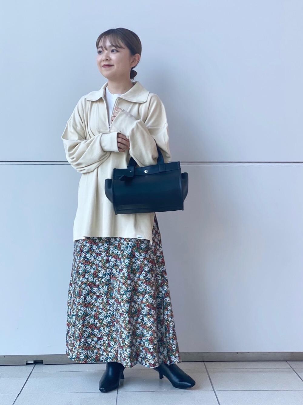 ブラック系のトートバッグ、ブラック系のブーツ、その他のスカートを着用したレディースの秋コーディネートの1枚目の写真