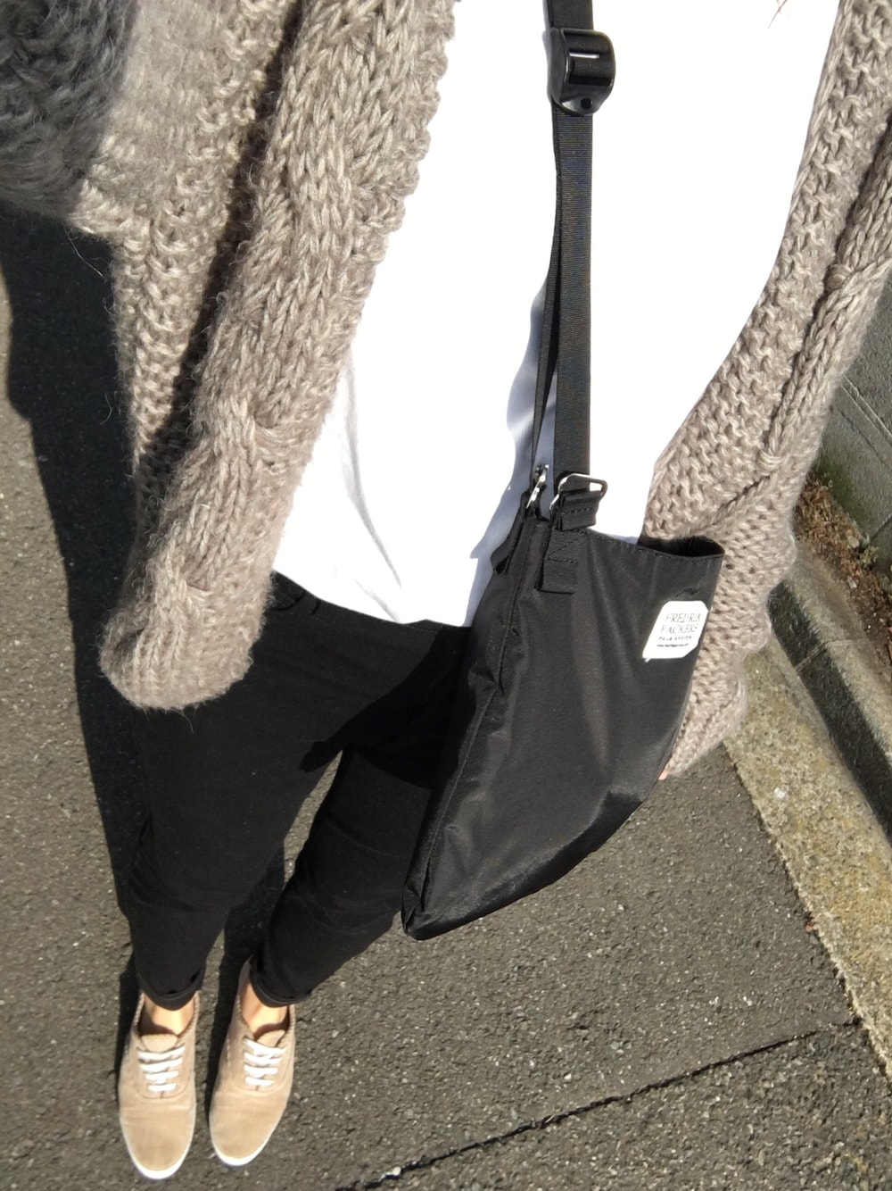 グレー系のカーディガン/ボレロ、ホワイト系のTシャツ/カットソー、ベージュ系のスニーカーを着用したレディースの冬コーディネートの1枚目の写真