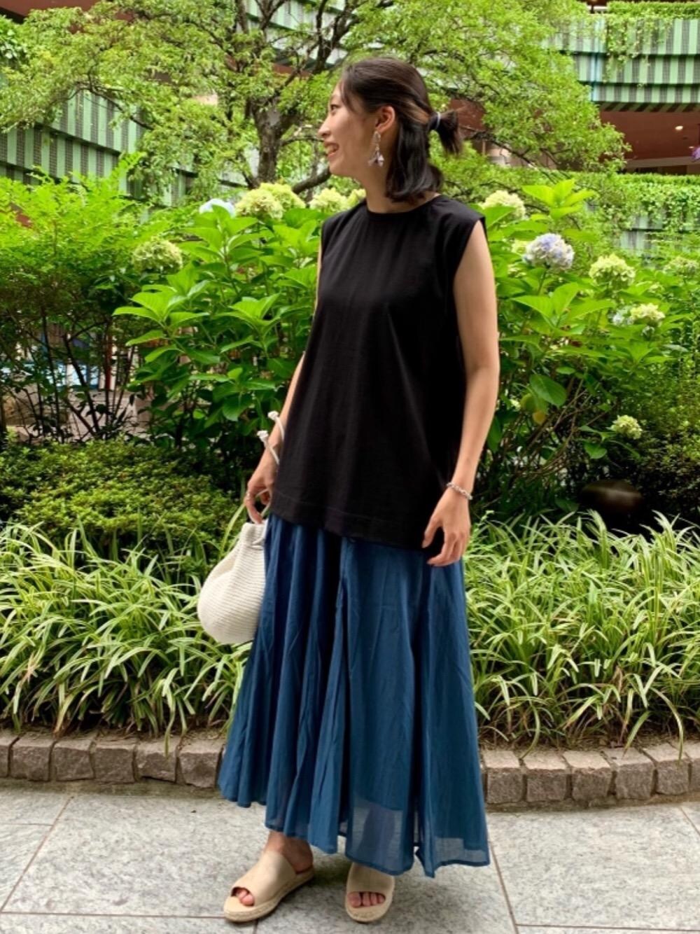 ブルー系のスカート、ベージュ系のサンダル、ホワイト系のショルダーバッグを着用したレディースの夏コーディネートの1枚目の写真