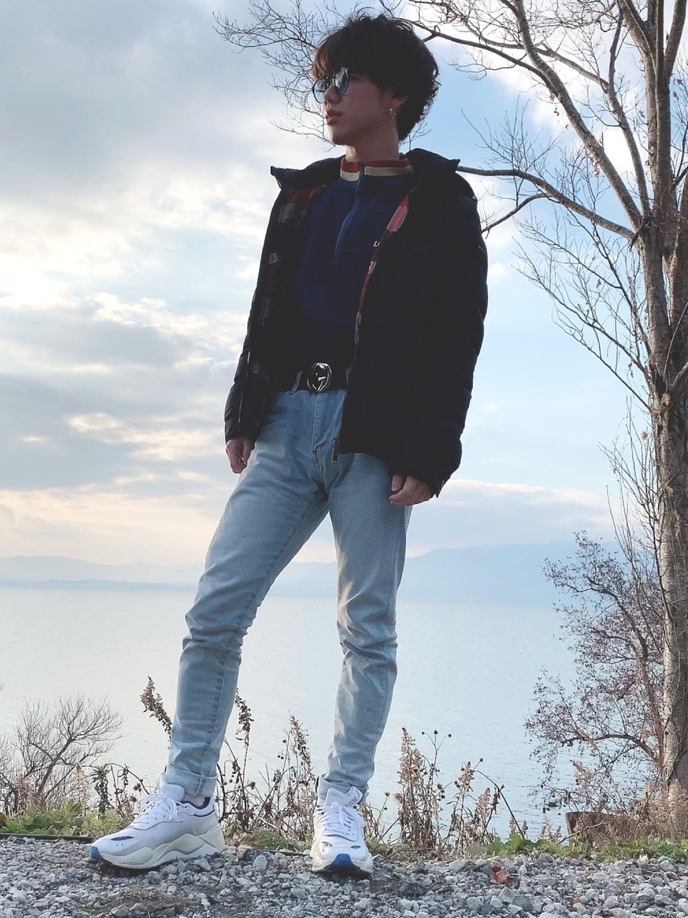 ホワイト系のスニーカー、ブルー系のデニムパンツ、ブラック系のダウンジャケット/コートを着用したメンズの冬コーディネートの1枚目の写真