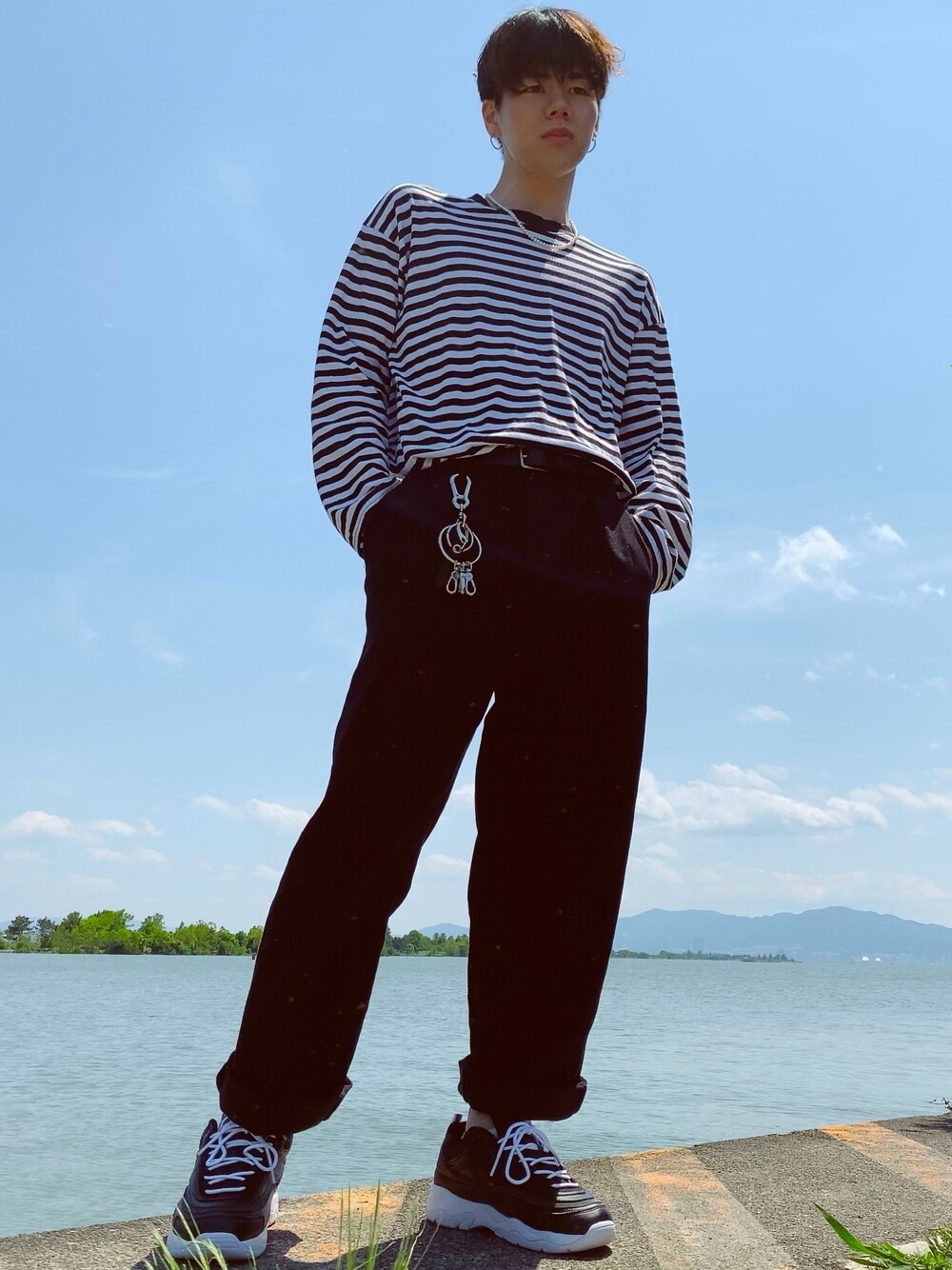 ブラック系のスニーカー、ブラック系のチノパンツ、ブラック系のトップスを着用したメンズの春コーディネートの1枚目の写真