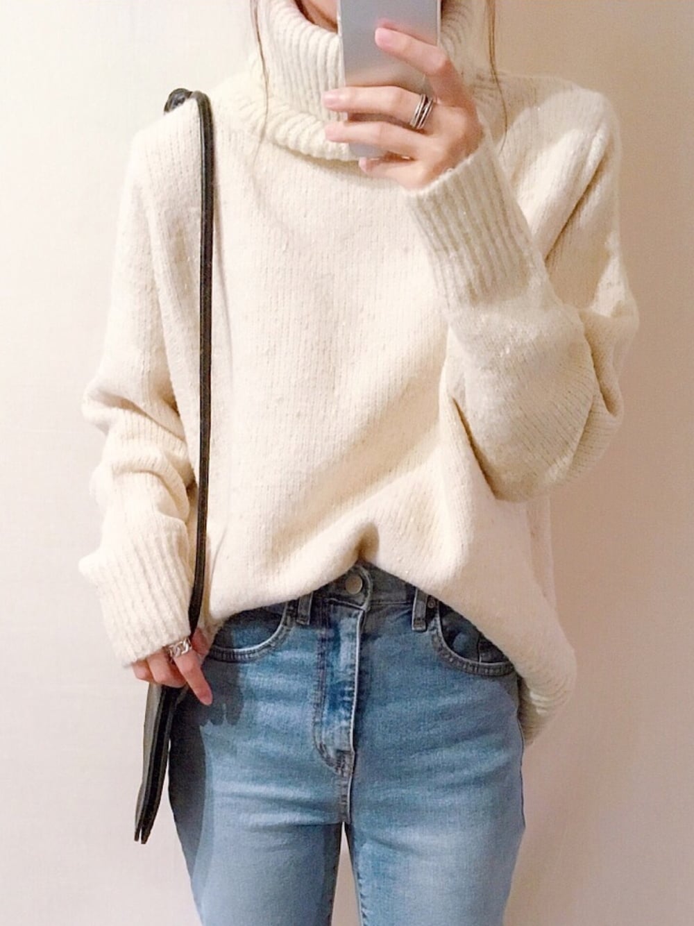 ホワイト系のニット/セーター、ブルー系のデニムパンツ、ブラック系のバッグを着用したレディースの秋コーディネートの1枚目の写真