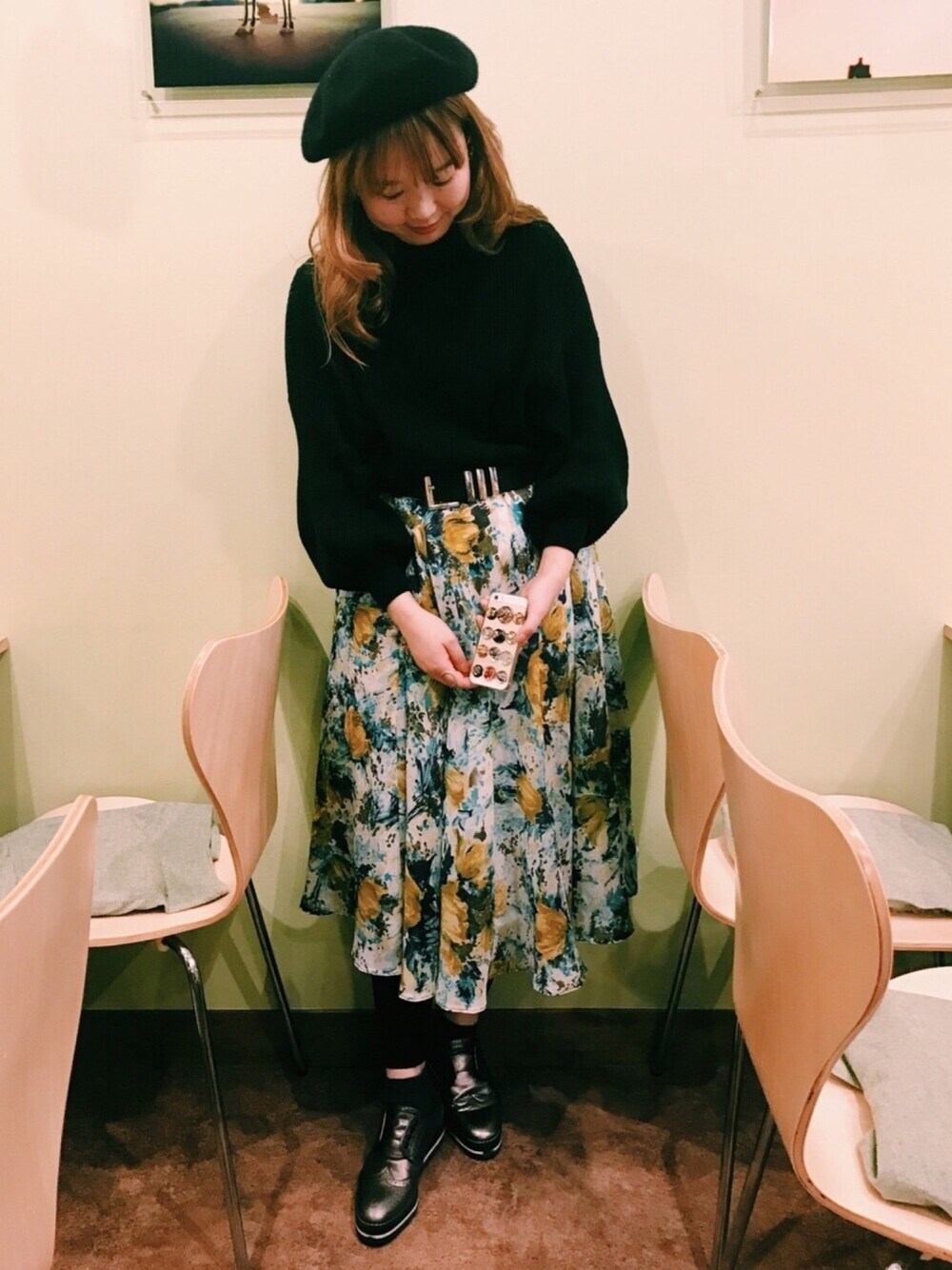 ブラック系のニット/セーター、グリーン系のスカート、その他のイヤリングを着用したレディースの春コーディネートの1枚目の写真