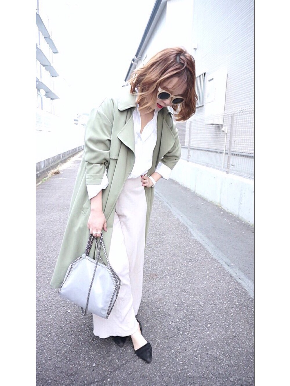 ブラック系のショルダーバッグ、グリーン系のトレンチコート、ホワイト系のシャツ/ブラウスを着用したレディースの春コーディネートの1枚目の写真