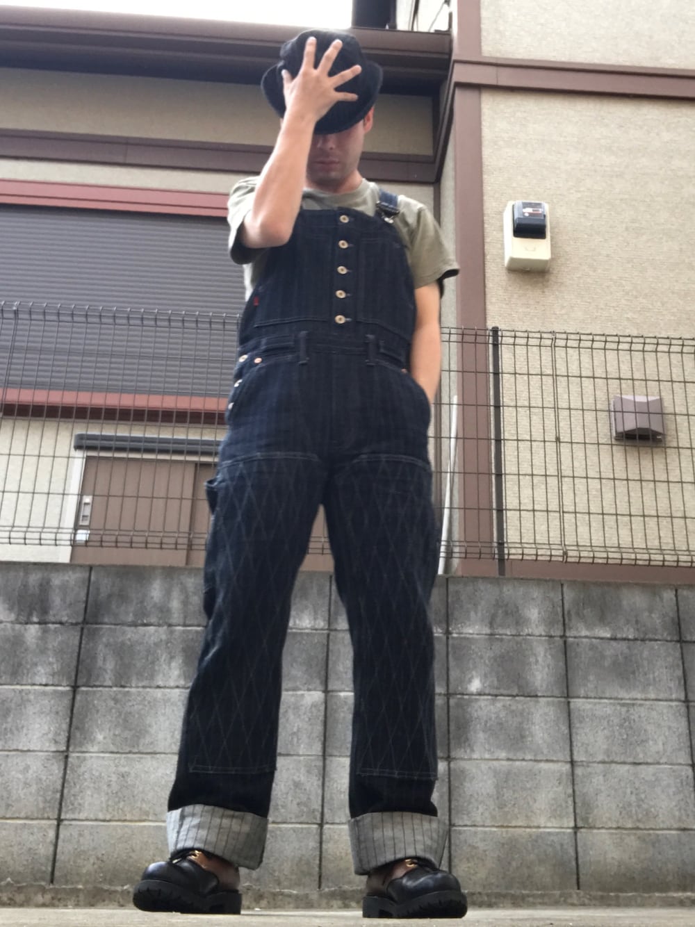 ブルー系のサロペット/オーバーオール、ブラック系のブーツ、ブラック系のハットを着用したメンズの春コーディネートの1枚目の写真