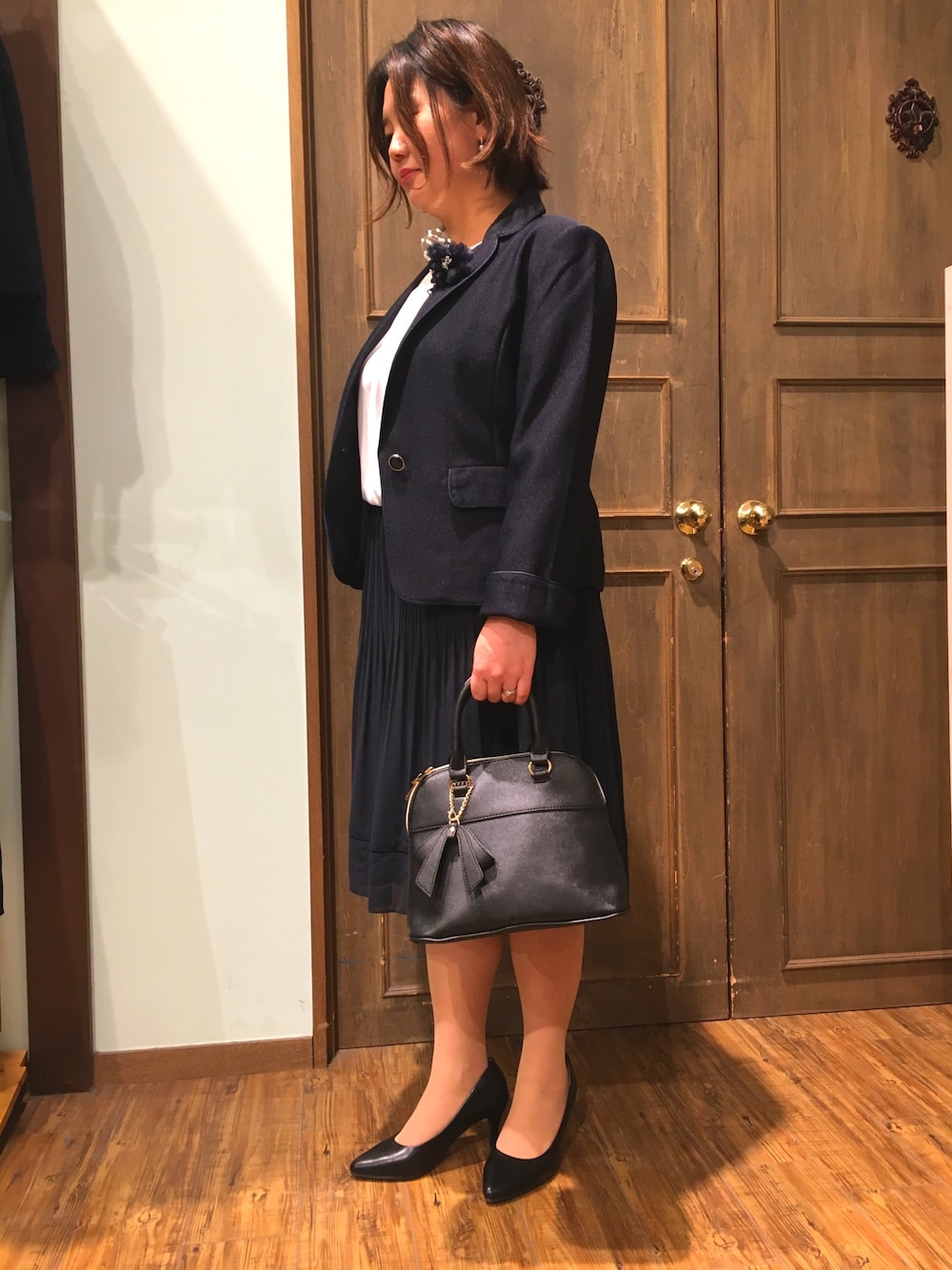 ブルー系のテーラードジャケット、ブルー系のスカート、ブラック系のパンプスを着用したレディースの冬コーディネートの1枚目の写真