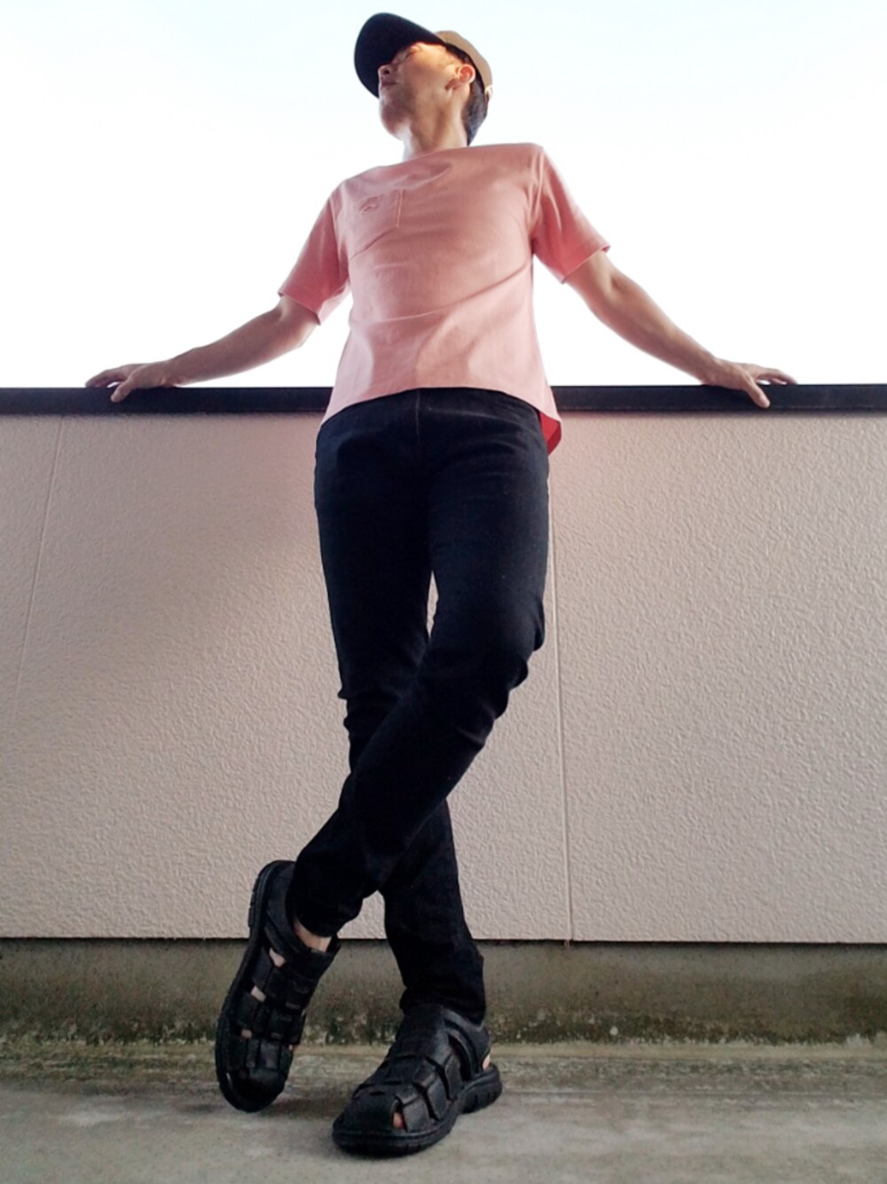 ピンク系のTシャツ/カットソー、ブラック系のデニムパンツ、ブラック系のサンダルを着用したメンズの夏コーディネートの1枚目の写真